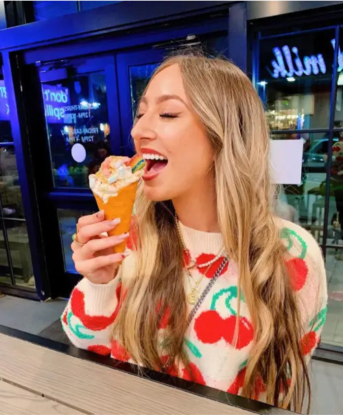 A woman sitting at the spilled milk bar eating her ice cream cone