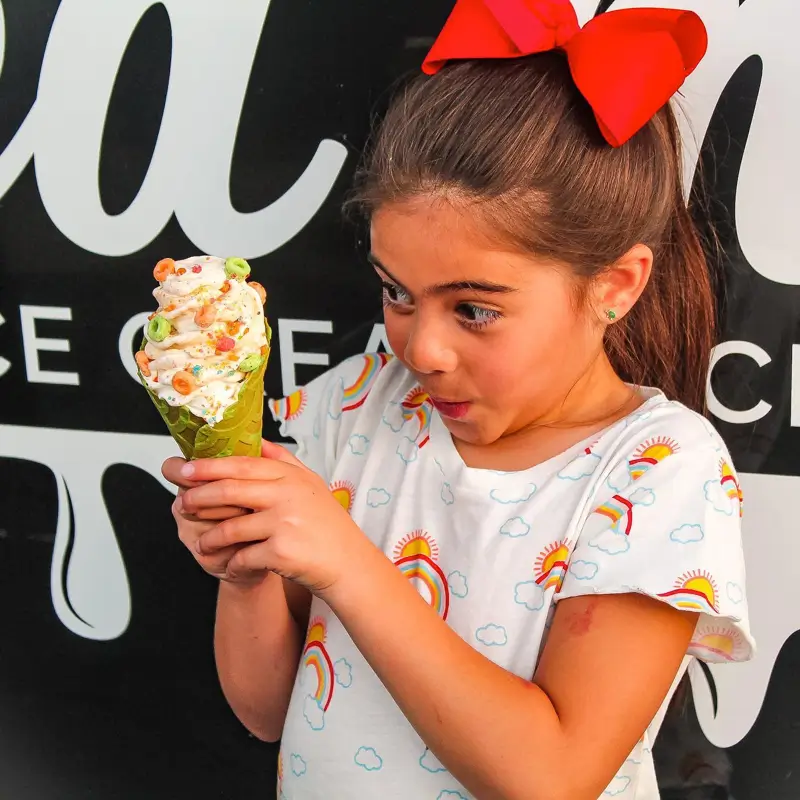 A young girl holding her ice cream cone outside of the Spilled Milk truck