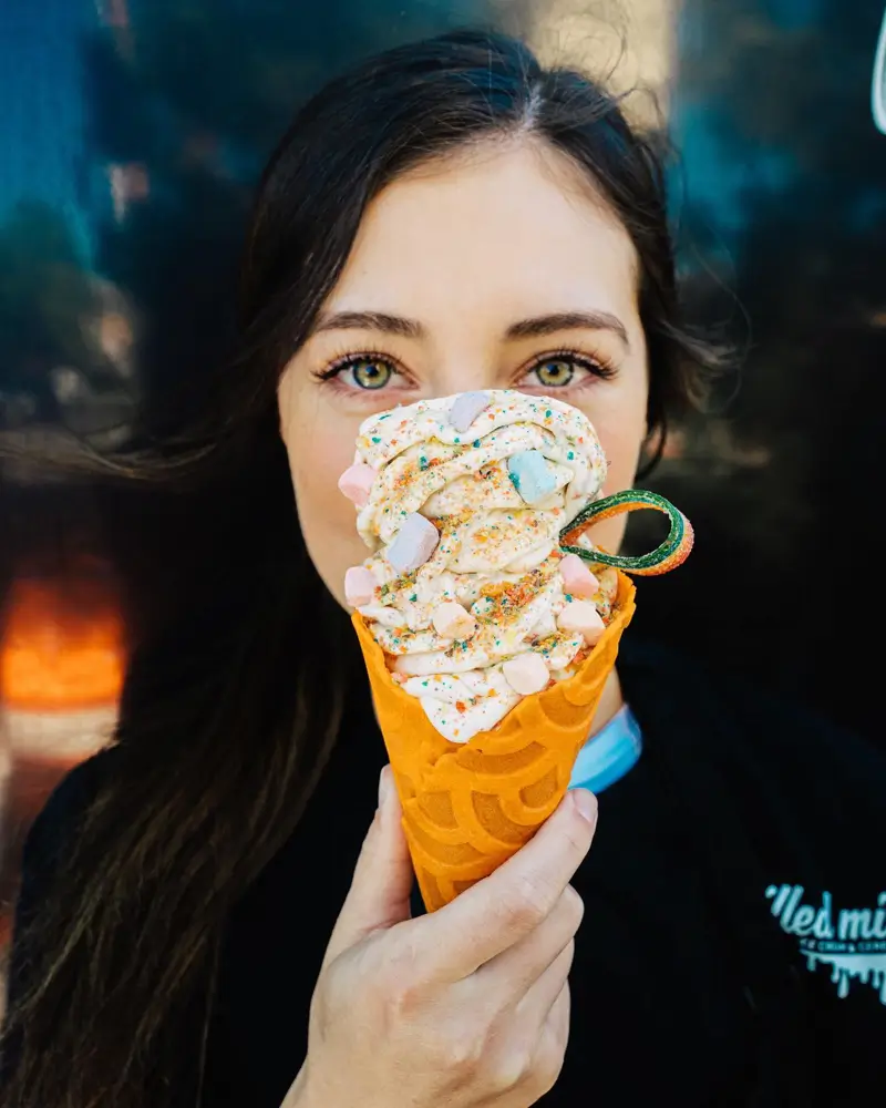 A woman holding her ice cream cone in front of her face