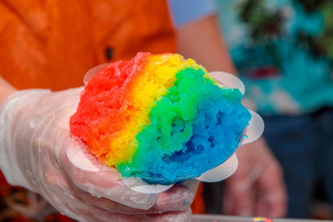 A woman holding out a rainbow shaved ice