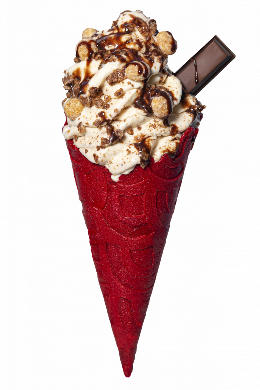 A red ice cream cone with vanilla icecream and many toppings