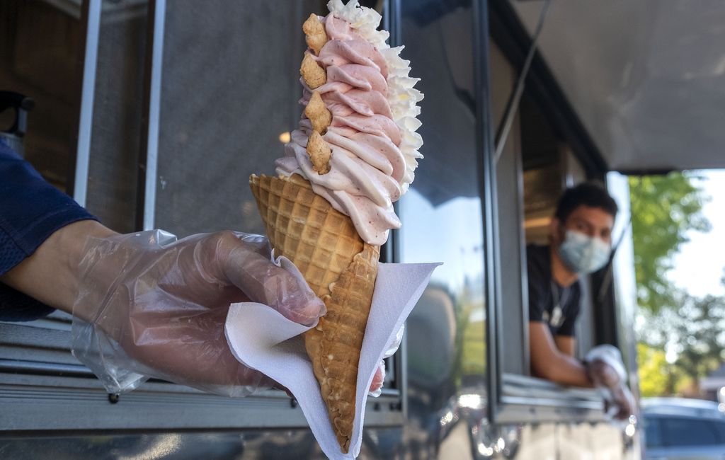 A man giving out an icecream cone from the side of a food truck